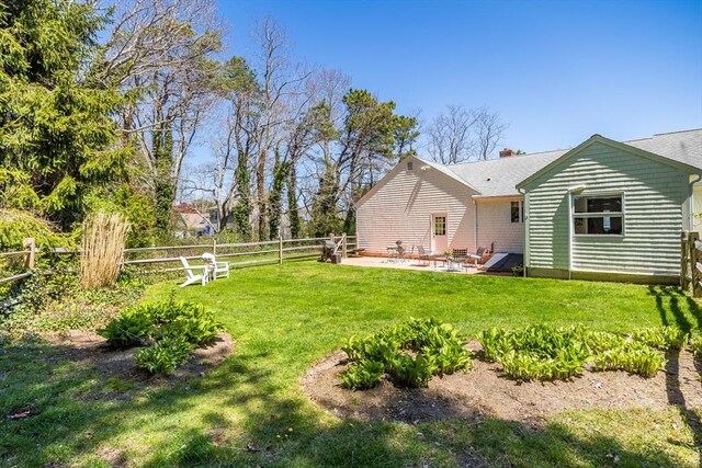 back of house featuring a fenced backyard, a patio, a chimney, and a lawn