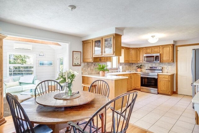 kitchen featuring light countertops, appliances with stainless steel finishes, decorative backsplash, and a wall mounted air conditioner