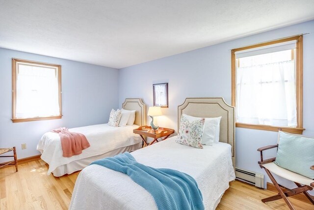 bedroom featuring wood finished floors and a baseboard radiator