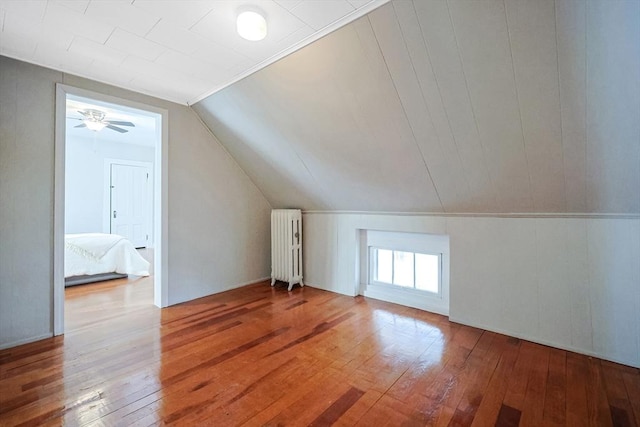 additional living space featuring lofted ceiling, radiator, and wood-type flooring