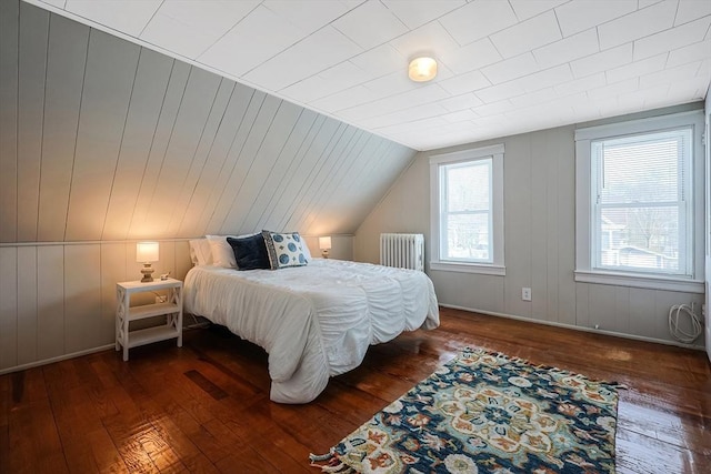 bedroom featuring lofted ceiling, radiator heating unit, and dark hardwood / wood-style floors