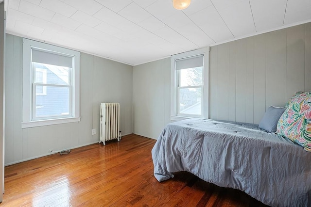 bedroom with radiator and hardwood / wood-style floors