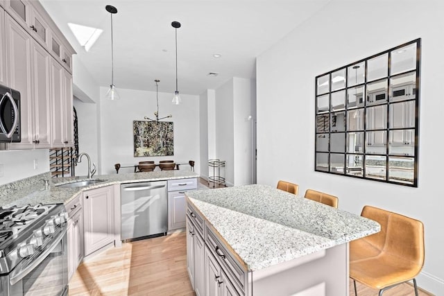 203 Middle St Unit 6, Weymouth, MA 02189 - kitchen with appliances with stainless steel finishes, a sink, light wood-style flooring, a kitchen island, and light stone countertops