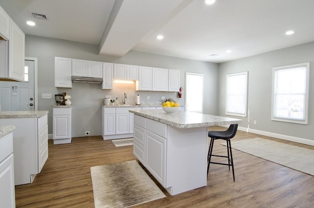 kitchen featuring white cabinetry, a kitchen bar, light wood-type flooring, and a kitchen island