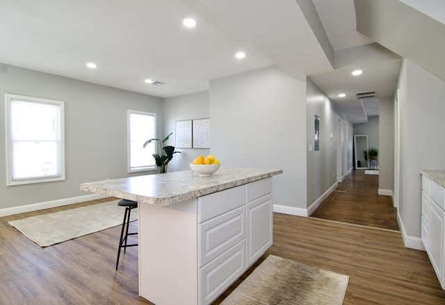 kitchen with a center island, dark wood-type flooring, white cabinets, and a kitchen breakfast bar