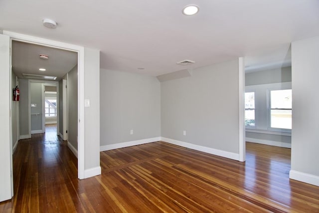 spare room featuring a healthy amount of sunlight and dark hardwood / wood-style flooring