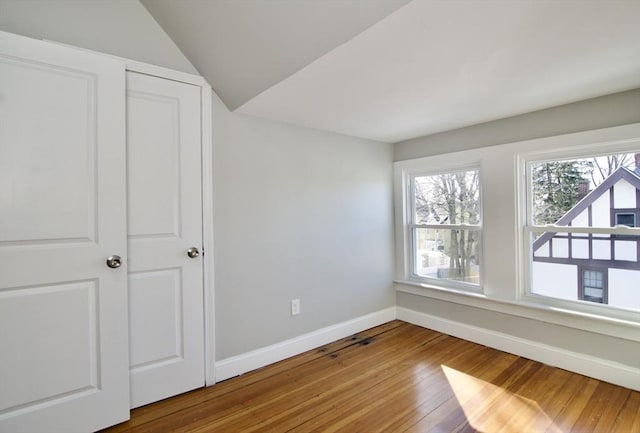 unfurnished bedroom featuring vaulted ceiling and hardwood / wood-style floors