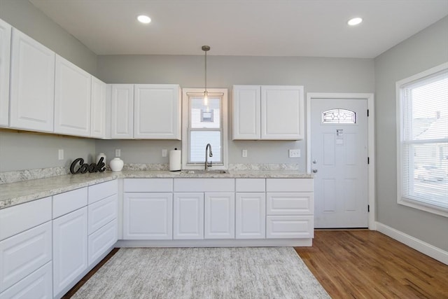 kitchen featuring pendant lighting, sink, light hardwood / wood-style flooring, and white cabinets