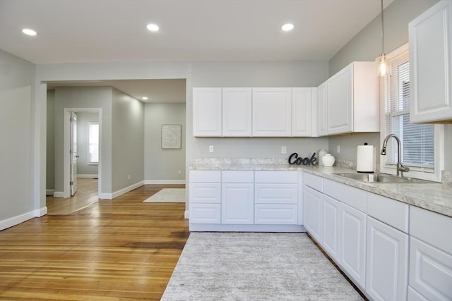 kitchen featuring white cabinetry, sink, pendant lighting, and light wood-type flooring