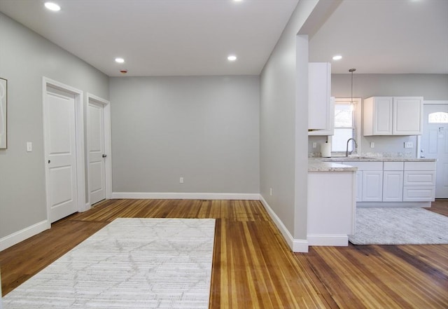 kitchen featuring hardwood / wood-style flooring, sink, white cabinets, and decorative light fixtures