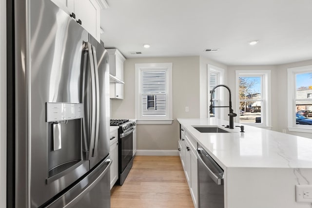 kitchen featuring white cabinets, sink, stainless steel appliances, and light hardwood / wood-style flooring