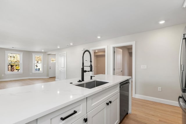 kitchen with dishwasher, white cabinets, sink, light wood-type flooring, and light stone counters