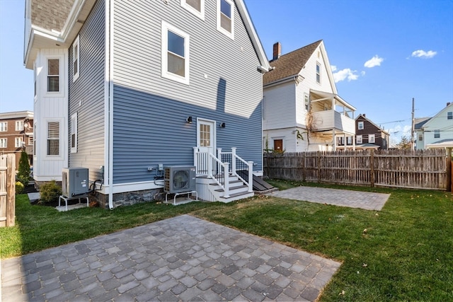 back of house with cooling unit, a patio area, and a yard