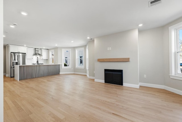 unfurnished living room with light wood-type flooring and sink