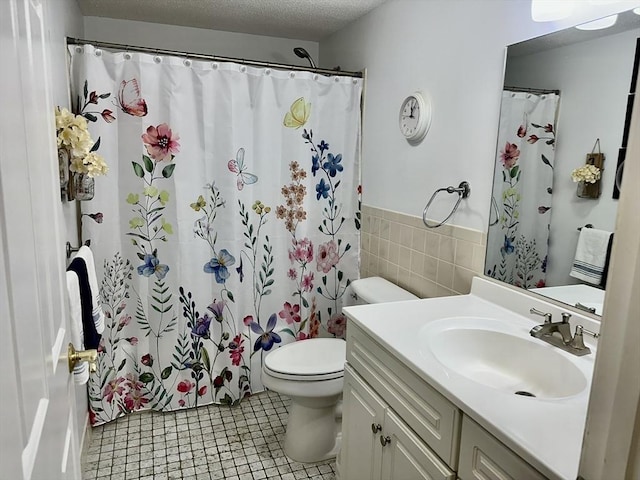 full bathroom with tile walls, toilet, a textured ceiling, vanity, and tile patterned flooring