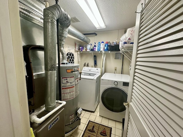 washroom featuring a textured ceiling, light tile patterned floors, gas water heater, washing machine and dryer, and laundry area