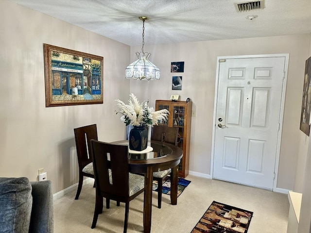 dining area featuring a textured ceiling, light carpet, visible vents, and baseboards