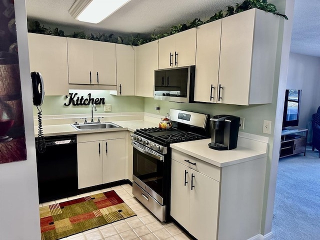 kitchen featuring light tile patterned floors, stainless steel appliances, a sink, white cabinets, and light countertops