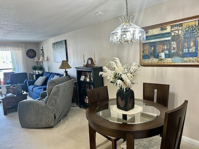 carpeted dining area with a chandelier and a textured ceiling