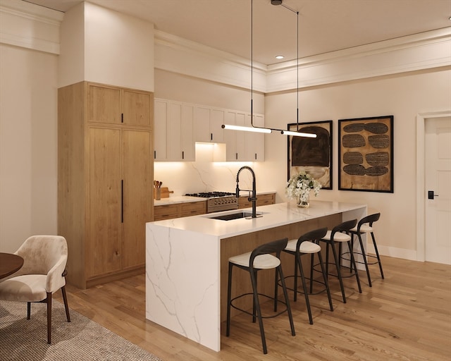 kitchen with sink, pendant lighting, white cabinets, crown molding, and light hardwood / wood-style flooring