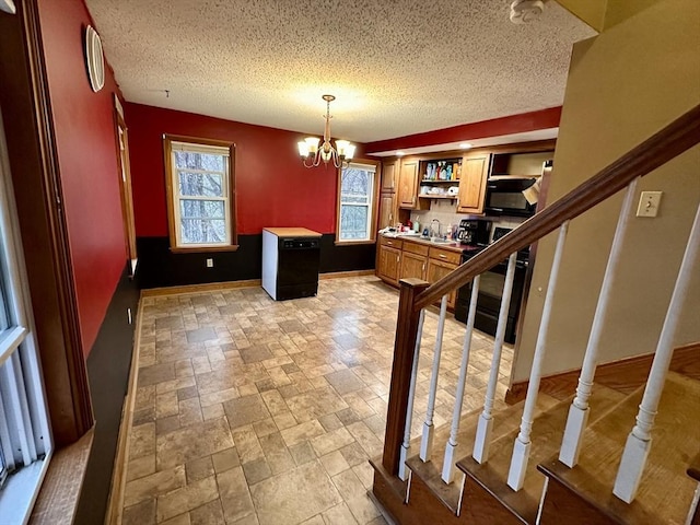 kitchen with a sink, black microwave, a textured ceiling, and a chandelier