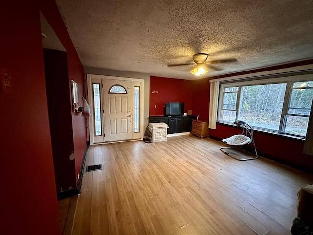 entryway featuring visible vents, baseboards, light wood-type flooring, a textured ceiling, and a ceiling fan