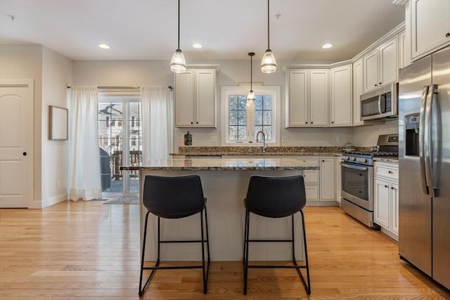 kitchen featuring stainless steel appliances, light stone countertops, hanging light fixtures, and white cabinets