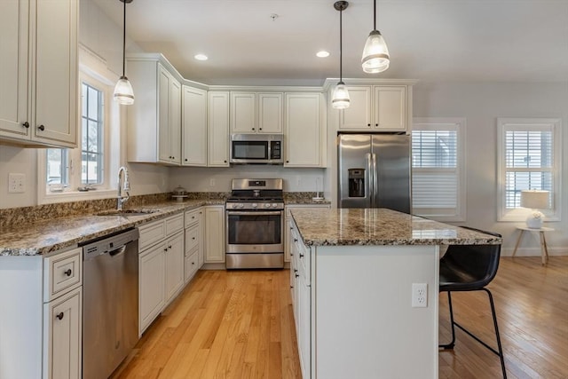 kitchen with sink, decorative light fixtures, stainless steel appliances, and a center island