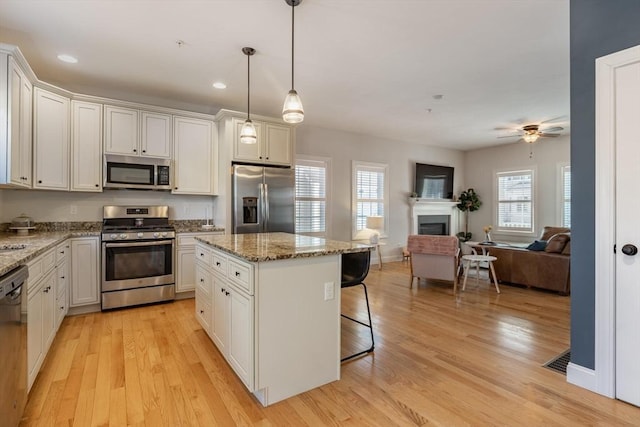 kitchen featuring stainless steel appliances, a kitchen island, a breakfast bar, and white cabinets