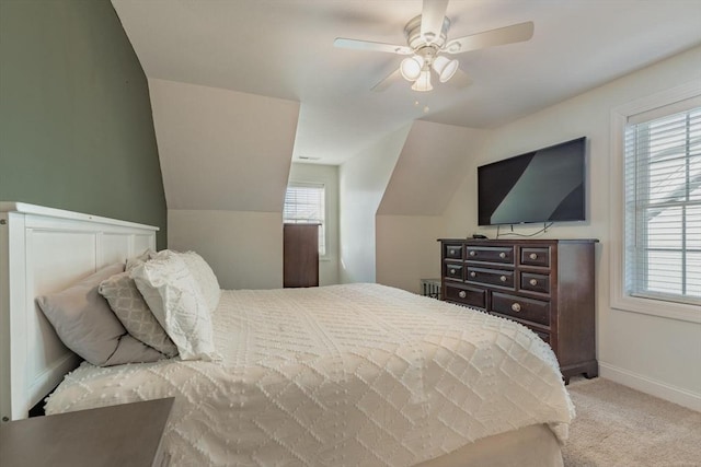 bedroom with ceiling fan, light colored carpet, vaulted ceiling, and multiple windows