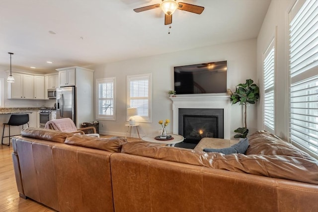 living room with ceiling fan and light wood-type flooring