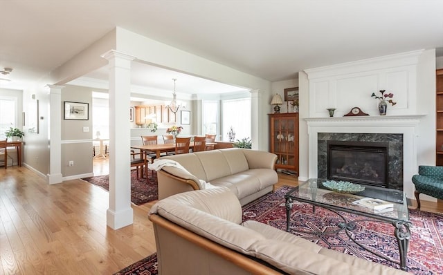 21 Harbor Mist Dr Unit 21, Fairhaven, MA 02719 - living area featuring ornate columns, light wood-style flooring, a premium fireplace, and a chandelier