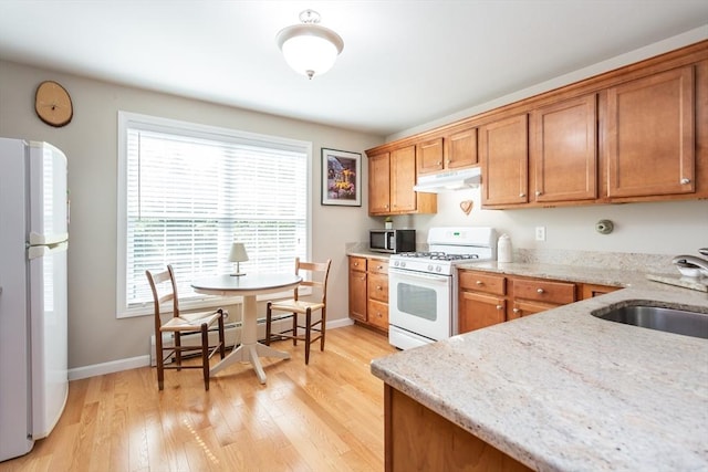21 Harbor Mist Dr Unit 21, Fairhaven, MA 02719 - kitchen featuring white appliances, under cabinet range hood, brown cabinets, light wood finished floors, and light stone countertops