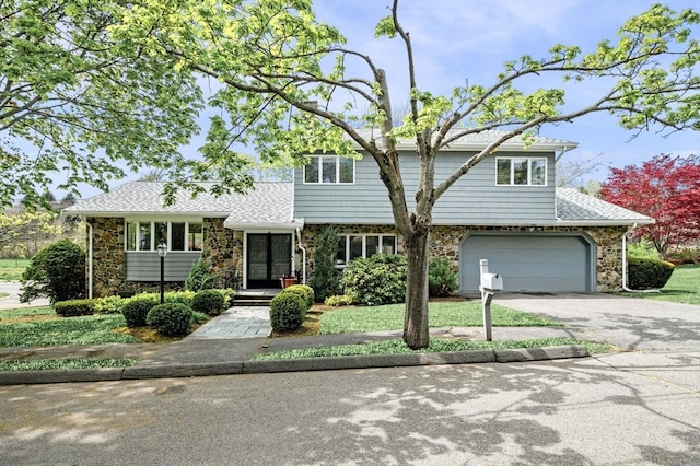 view of front of property featuring stone siding, roof with shingles, a garage, and aphalt driveway