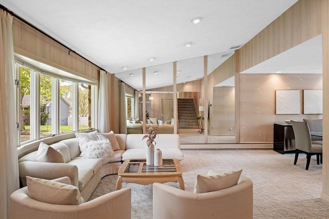 carpeted living area with a wealth of natural light, wooden walls, and lofted ceiling