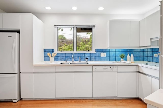 kitchen with light countertops, a sink, and white appliances