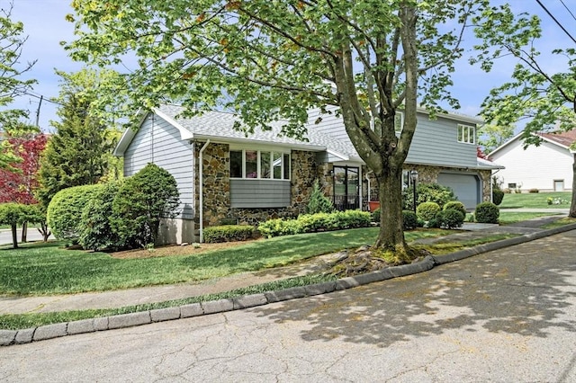 view of front of property featuring stone siding, an attached garage, and a front yard