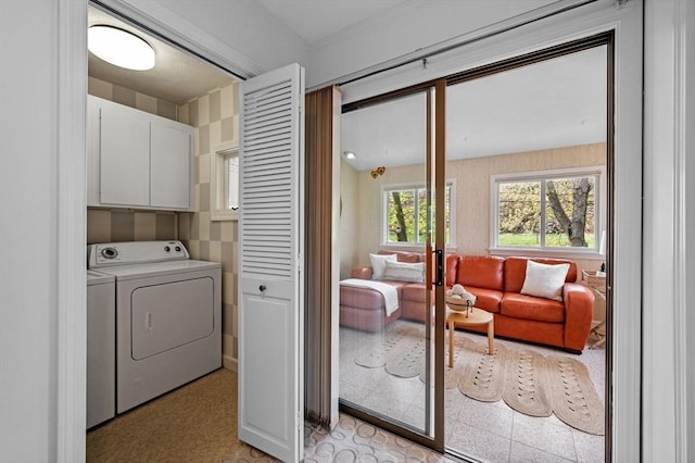 clothes washing area featuring washer and clothes dryer, light floors, and cabinet space