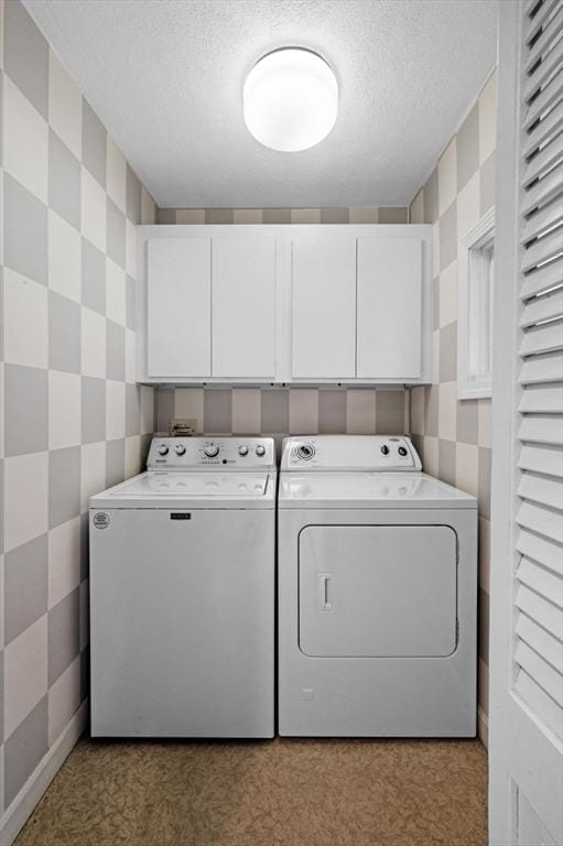washroom with a textured ceiling, cabinet space, and washer and dryer