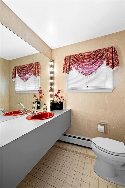bathroom with toilet, a baseboard radiator, tile patterned floors, and a sink