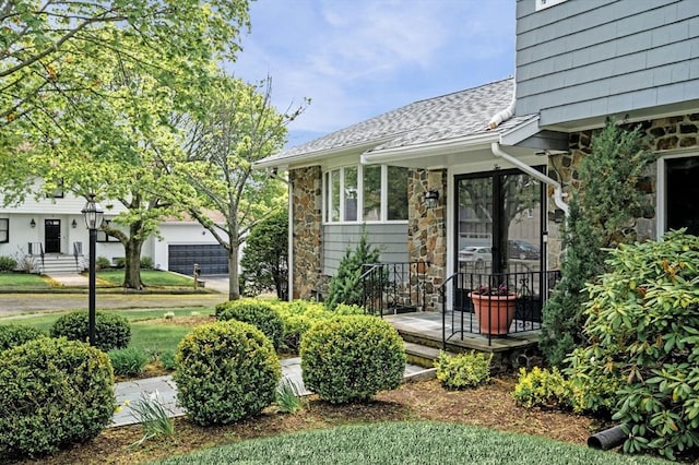 exterior space with stone siding and roof with shingles
