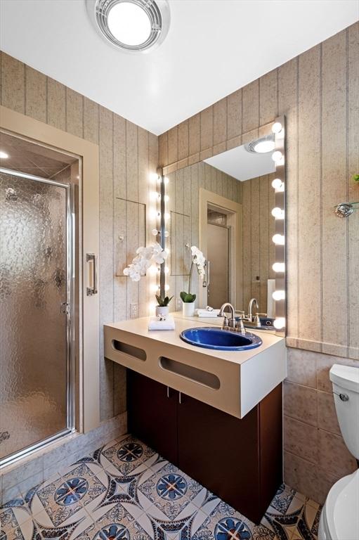 full bathroom with toilet, tile walls, tile patterned flooring, a shower stall, and vanity