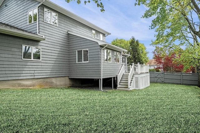 back of house featuring a wooden deck, fence, a lawn, and stairway