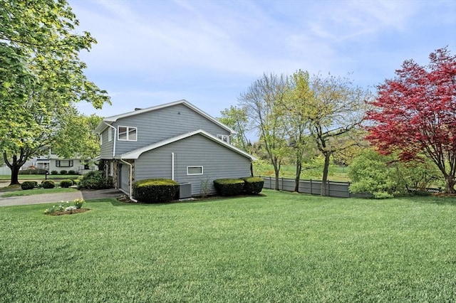 view of property exterior featuring central air condition unit, fence, driveway, a yard, and a garage