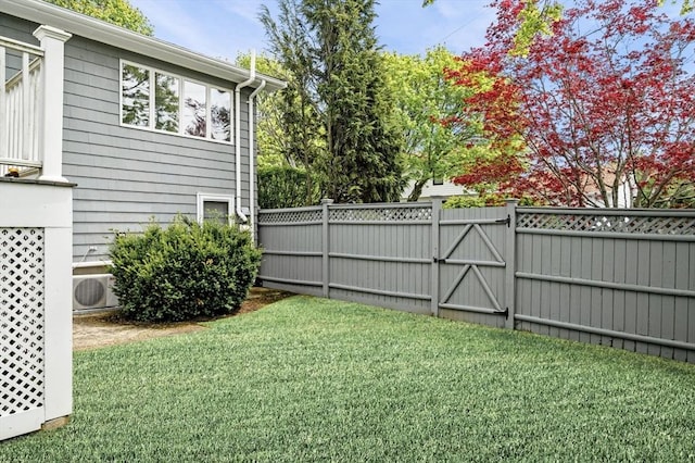 view of yard with a gate, fence, and ac unit