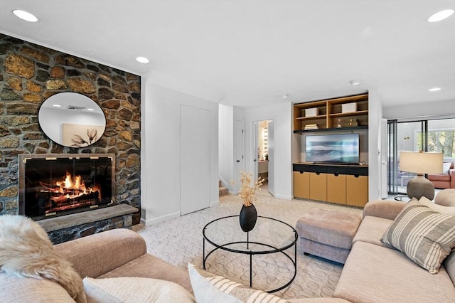 living room with baseboards, a stone fireplace, and recessed lighting