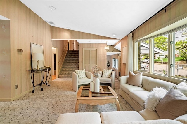 living room featuring baseboards, stairs, wood walls, vaulted ceiling, and light colored carpet