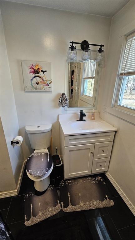 half bath with baseboards, vanity, and toilet