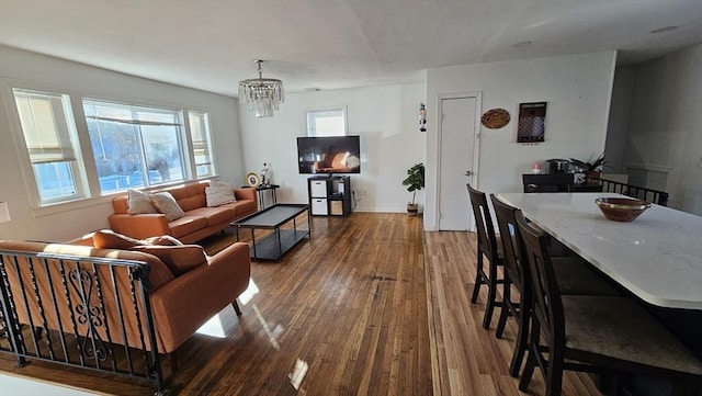 living area featuring a chandelier, dark wood-style flooring, and baseboards