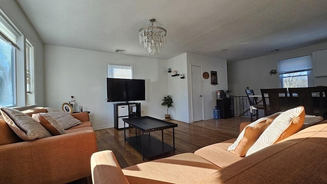 living room with a notable chandelier, plenty of natural light, visible vents, and wood finished floors